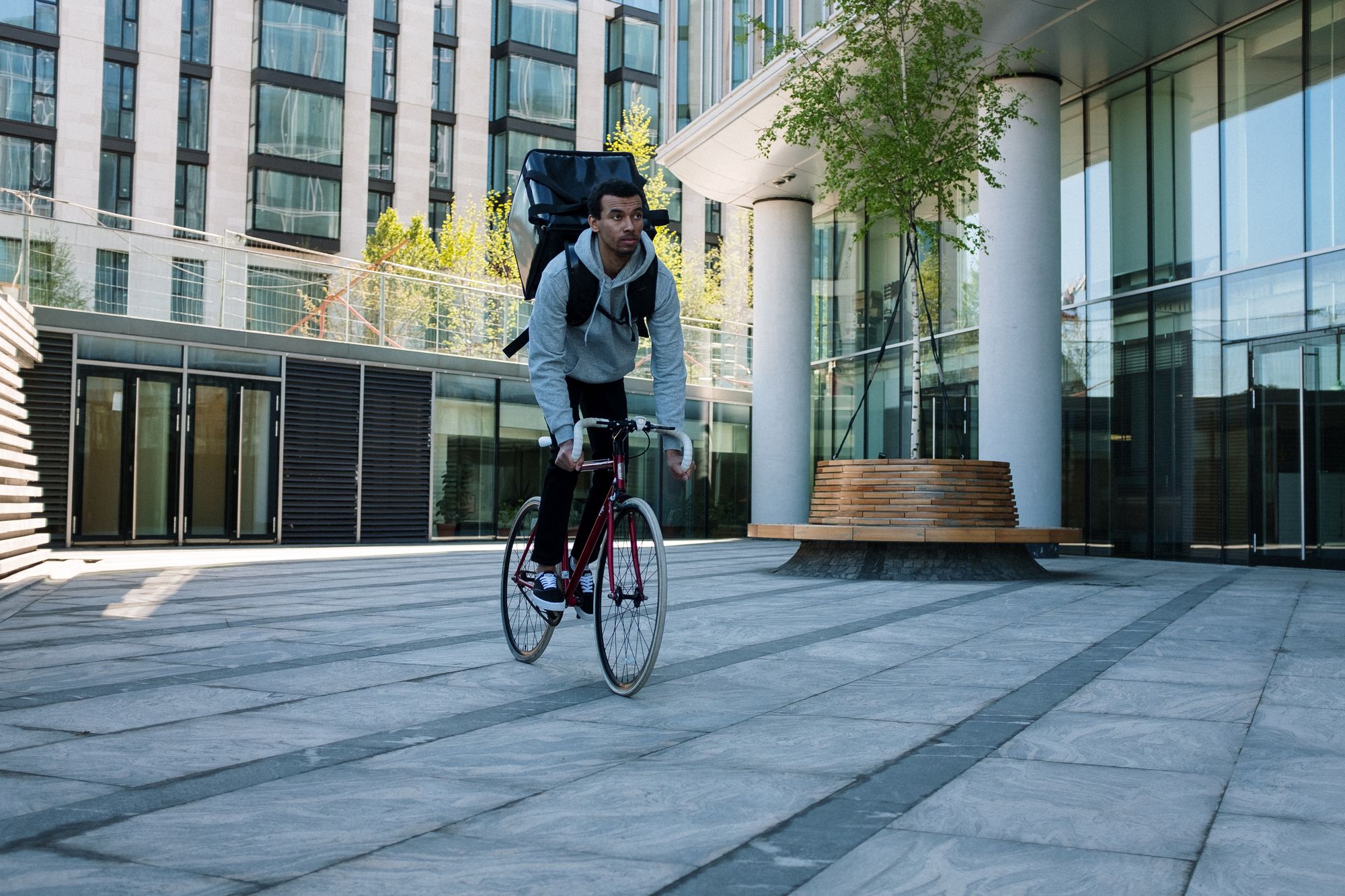 Fahrradkurier vor moderner Gebäudearchitektur unterwegs zur Zustellung