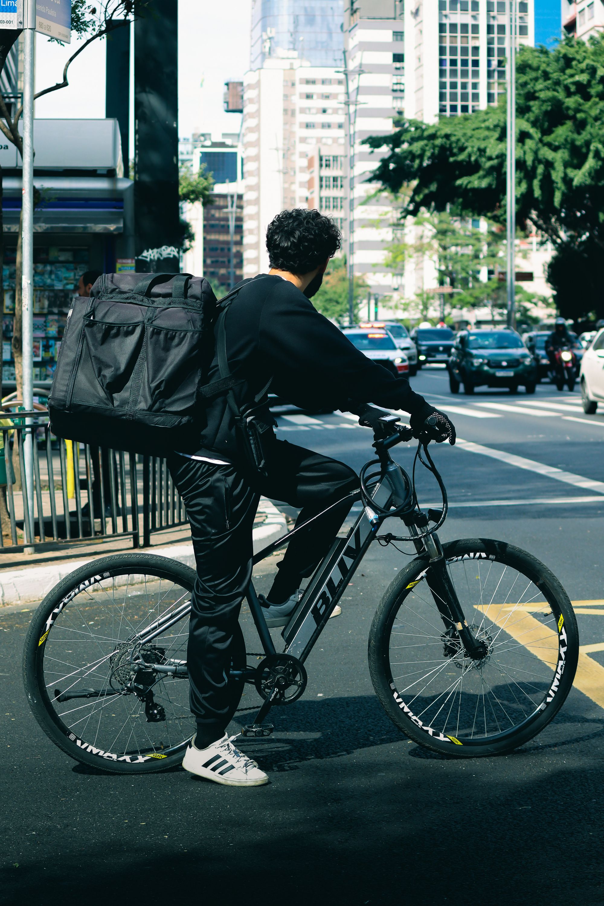 Fahrradkurier wartet an einer urbanen Kreuzung bei Dämmerung
