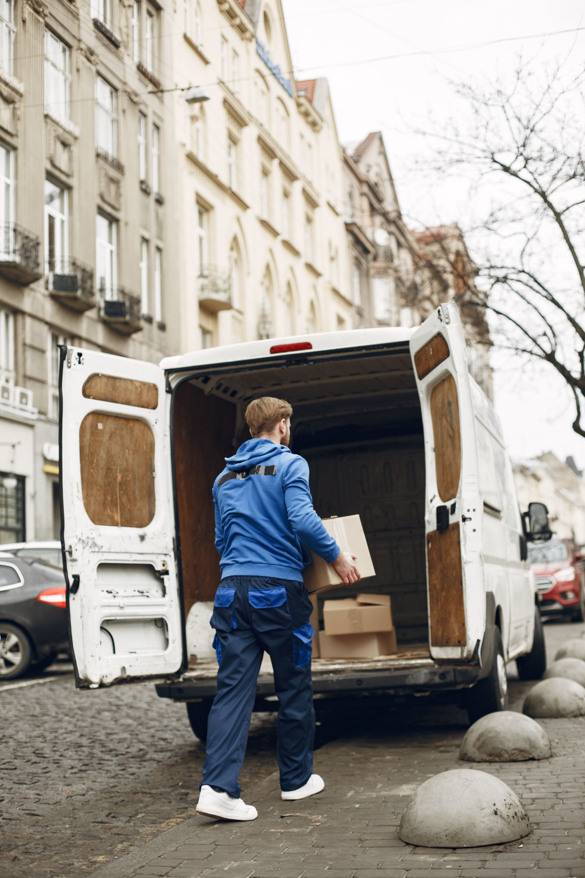 Kurier-Transporter mit geöffneter Heckklappe auf einer gepflasterten Straße, bereit zur Auslieferung