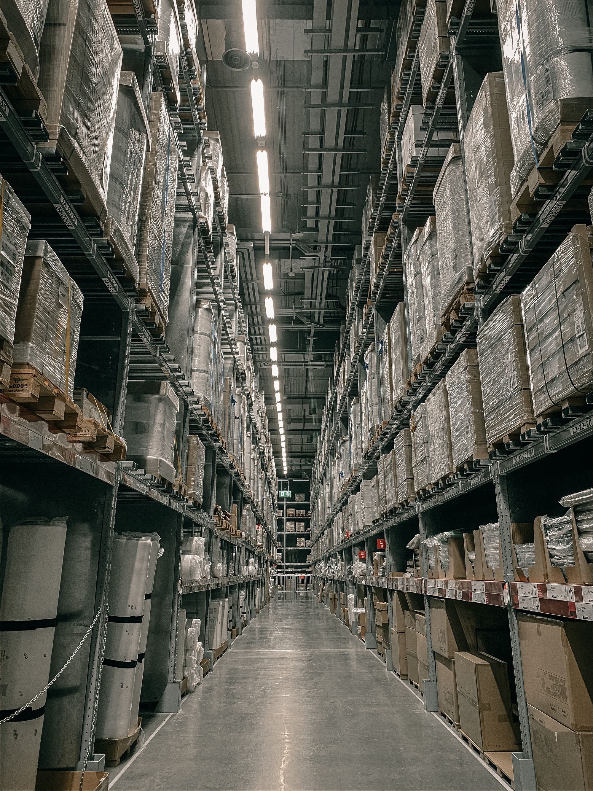 Großes Logistiklager mit hohen Palettenregalen und eingelagerter Ware